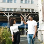 High five between a smiling young couple outside an urban building, symbolizing successful property investment and real estate opportunities in Tanzania.